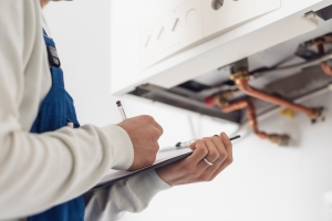 Technician Monitoring Boiler Issues and Writing on Paper