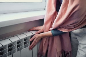 Woman Checking Heat Flow of Radiator Near Window