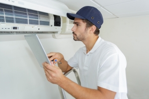Technician Tuning Up AC Unit in Spring