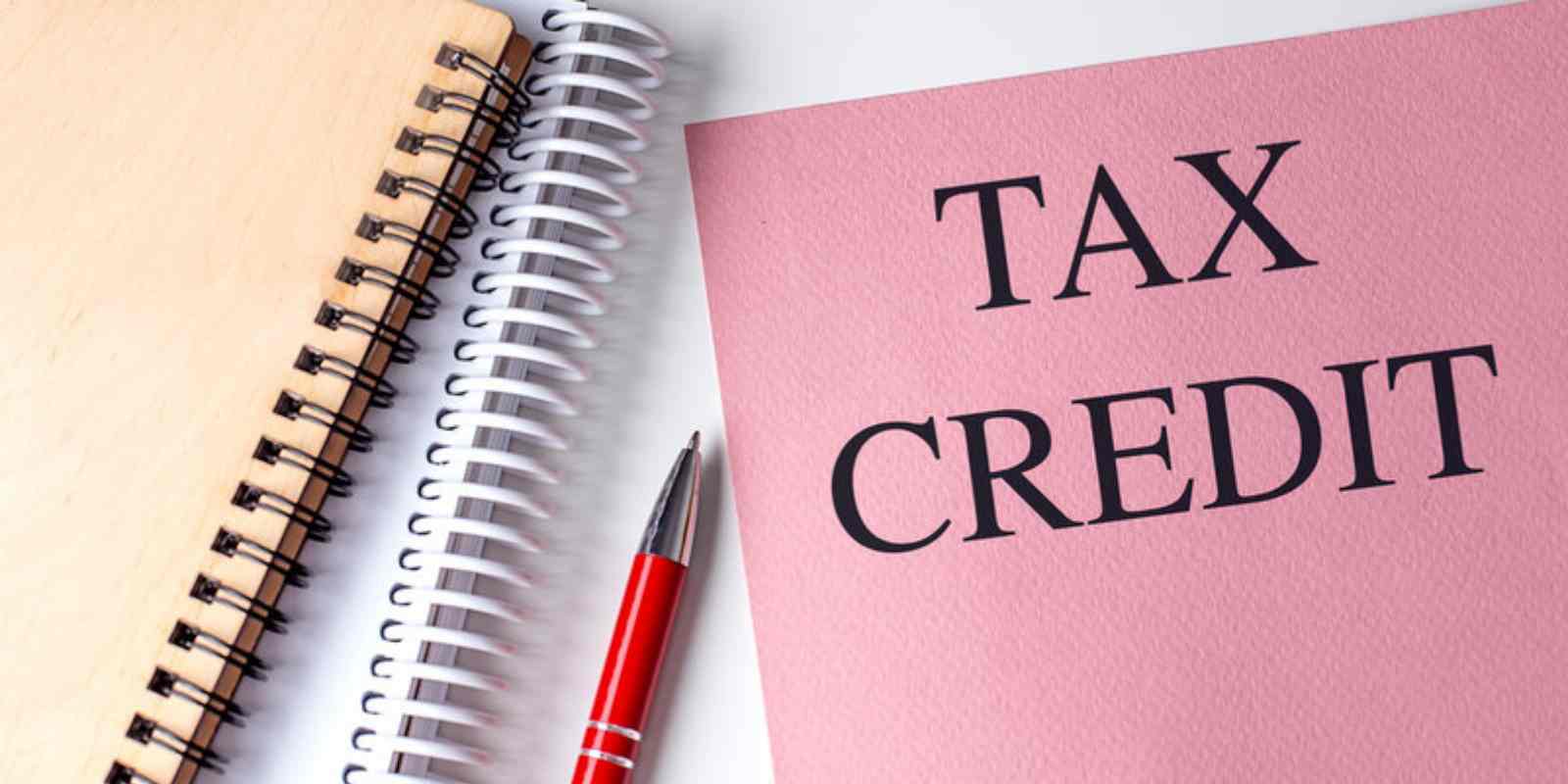 Pink Folder with The Words Tax Credit Next to Spiral Notebooks