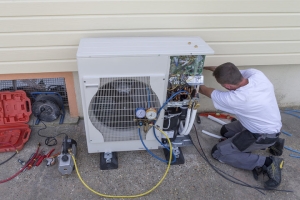 Professional HVAC Technician Installing Electric Heat Pump Outside a House