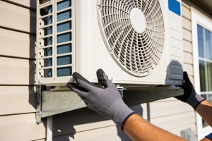 Technician Installing Outdoor Unit of Mini Split onto a House Wall