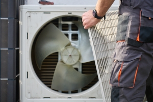 Technician Removing front Cover Grille From Outdoor Heat Pump Unit for Repair